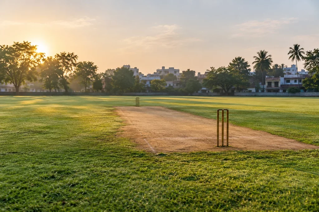 An empty neighbourhood cricket ground in India under soft morning light.